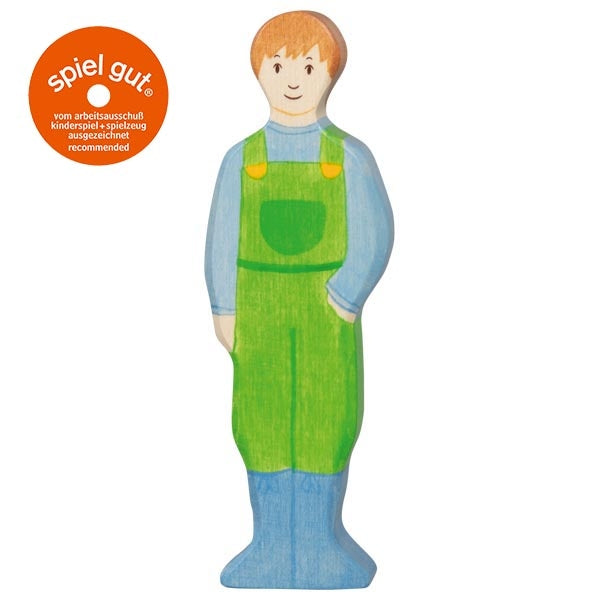 Wooden toy figure of a boy wearing green overalls with 'spiel gut' logo on a white background