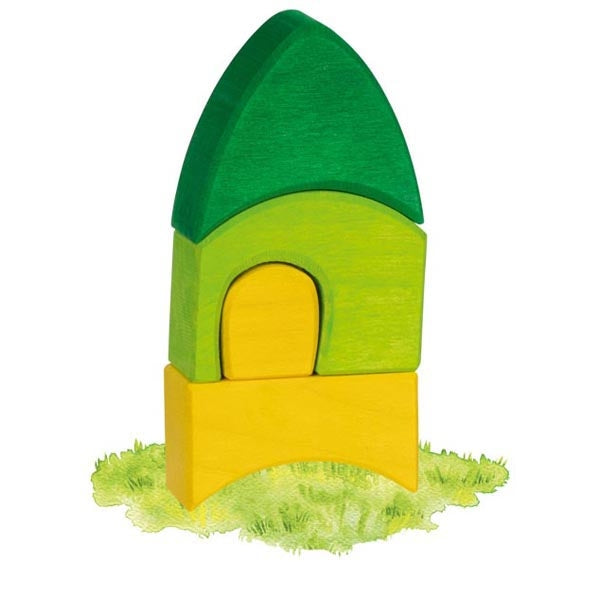 A wooden toy house block with a green roof, lime green body, yellow door, and yellow base, standing on a small patch of textured green grass against a white background.