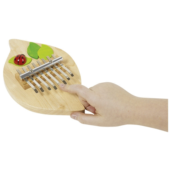 Wooden kalimba with a hand playing it on a white background