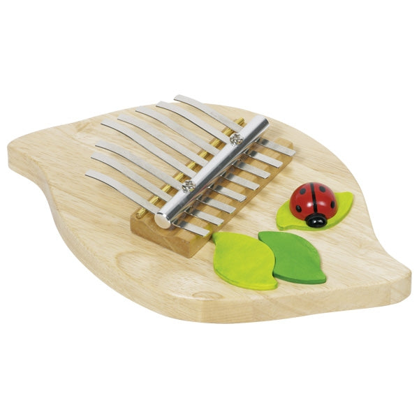 Wooden kalimba with ladybug and leaves on a white background