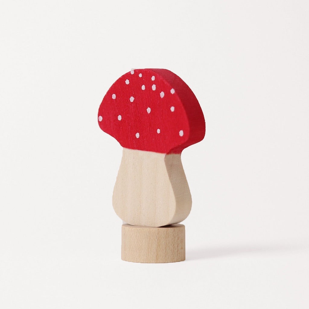 A small wooden toy mushroom with a red cap decorated with white spots, a light natural wood stem, and a round natural wood base, photographed on a clean white background.
