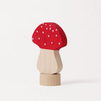 A small wooden toy mushroom with a red cap decorated with white spots, a light natural wood stem, and a round natural wood base, photographed on a clean white background.