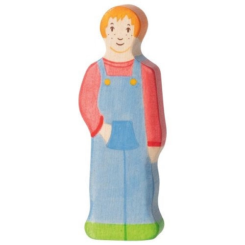 Wooden toy figure of a child wearing a red shirt and blue overalls on a white background